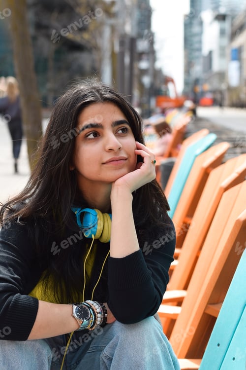 Preview: Young girl sitting on city street thinking, daydreaming