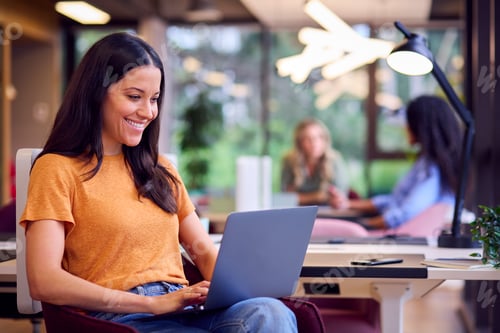 Preview: Businesswoman Sitting At Desk In Office Working On Laptop
