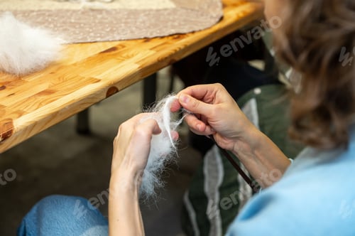 Preview: Woman's hands felting wool on wooden table surface in artisan workshop