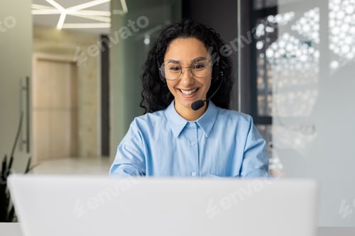Preview: Young beautiful woman with video call headset working inside office at workplace, Hispanic online