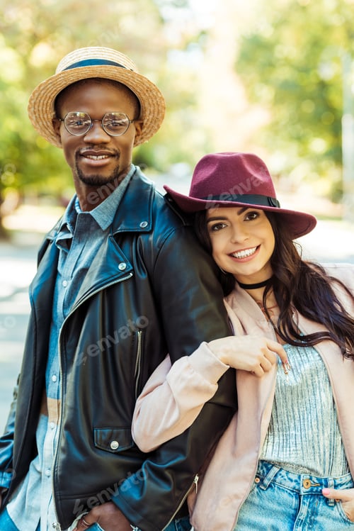 Preview: smiling Girlfriend hugging her boyfriend in straw hat on a street