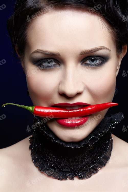 Preview: Portrait Of Beautiful Brunette Girl Biting Spicy Hot Red Cayenne Chili Pepper