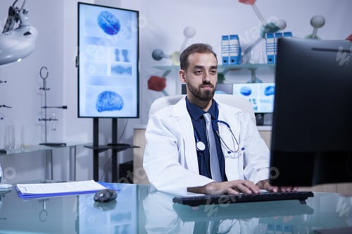 Preview: Young doctor siting at this computer typing a recipe for a patient