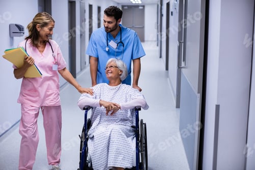 Preview: Male and female doctor interacting with female senior patient on wheelchair in corridor