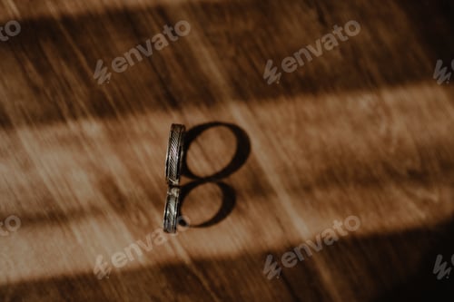 Preview: High angle shot of wedding rings on the wooden surface with shadow
