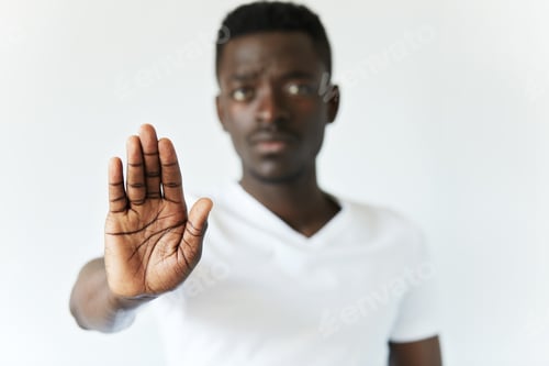 Preview: Headshot of young black African man wearing white T-shirt, looking at camera with serious face expre