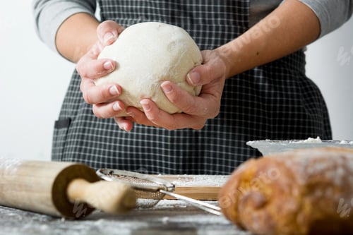 Preview: Baker holding fresh dough for baking bread or pizza