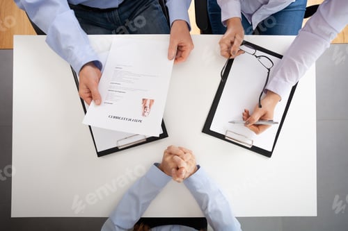 Preview: Top view of white table and people with legal pad and cv during recruitment interview