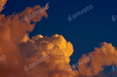 Preview: Fluffy clouds tinted orange by the sunset