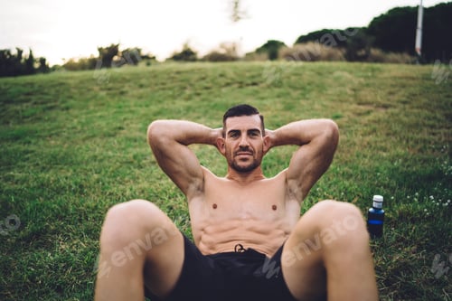 Preview: Shirtless sportsman practice ABS exercises toning strength during cardio workout in park