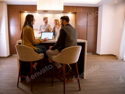 Preview: Group of young people preparing meal, looking for recipes on the laptop and having a good time