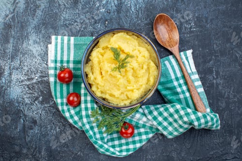Preview: Top view of mashed potatoes served with dill wooden spoon fresh tomatoes on green stripped towel on