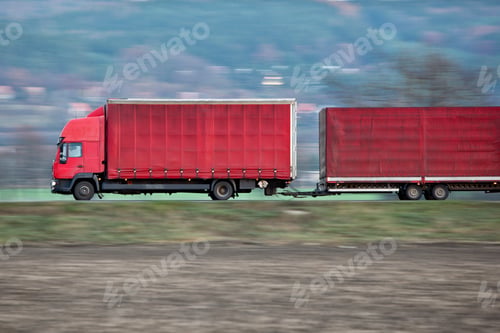 Preview: red camion/truck goes fast on a road (panned image - motion blur
