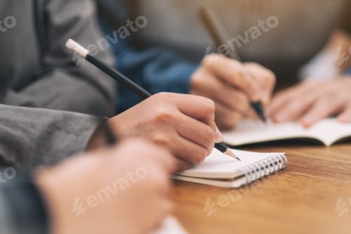 Preview: Closeup image of many people writing on blank notebook together on wooden table