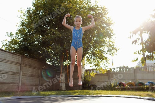 Preview: little sports girl jumps on a trampoline. Outdoor shot of girl jumping on trampoline, enjoys jumping