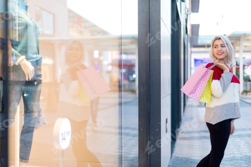 Preview: Smiling woman walking on the street with shopping bags