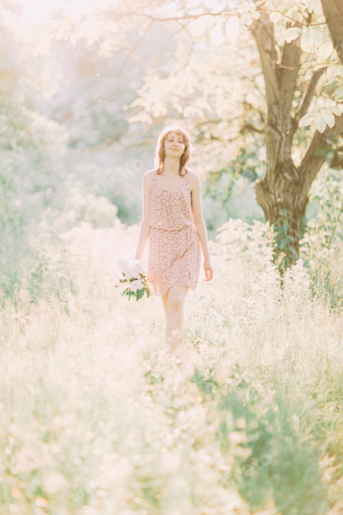 Preview: Beautiful young Caucasian blond woman in light dress holding bouquet of white peonies