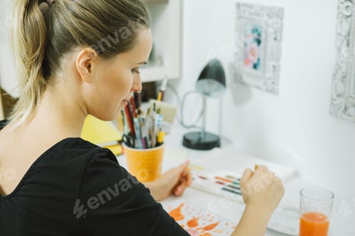 Preview: Back view of Young female artist drawing sketch at her workplace in studio