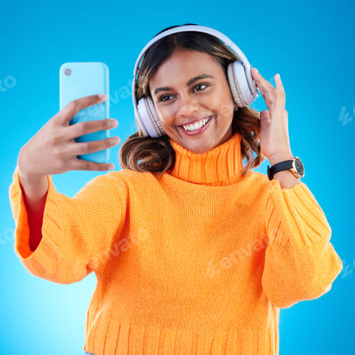 Preview: Music headphones, smile and selfie of woman in studio isolated on a blue background. Profile pictur
