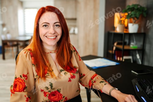 Preview: Portrait of a smiling red-haired woman at a desk
