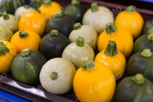 Preview: Yellow green and white pumpkins are laid in a row on the counter in the rural market. Natural Bio