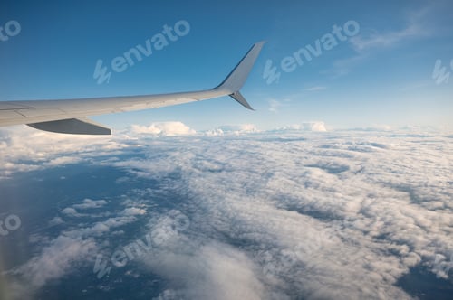 Preview: Wing of an airplane flying over white cloud in the sky during the vacation