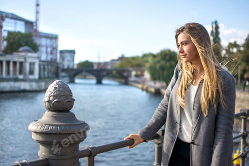 Preview: Young blonde woman standing near the river and enjoying a beautiful view.