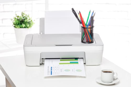 Preview: Printer in a bright office printing documents with a cup of coffee and colorful pens nearby