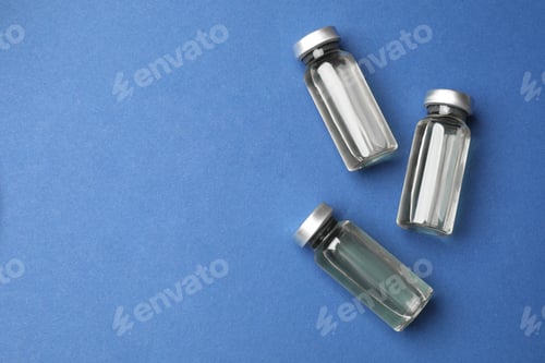 Preview: Hepatitis vaccine in glass vials on blue background, flat lay. Space for text