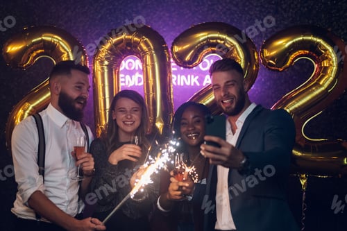 Visualização: Feliz grupo de amigos comemora a véspera de Ano Novo e tira uma selfie com um smartphone