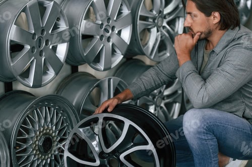 Preview: Thinking, choosing. Man is in the tire fitting car service