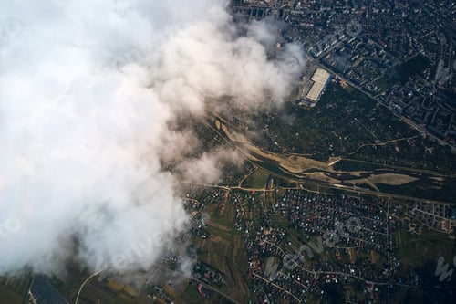 Preview: Aerial view from airplane window at high altitude of distant city covered with puffy cumulus clouds