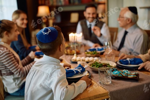 Preview: Rear view of Jewish boy having lunch with his extended family on Hanukah.