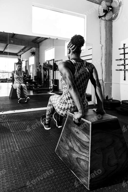 Preview: Fitness-focused woman is performing a strength-training exercise, performing dips in a gym