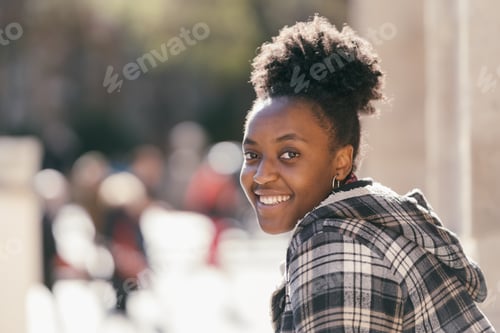 Preview: Smiling african woman turning to the camera outdoors