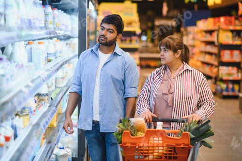 Preview: Indian couple choosing products in dairy section of grocery store