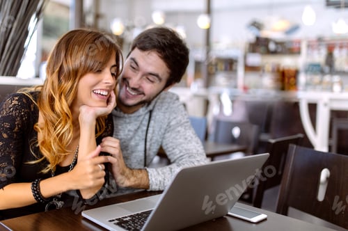 Preview: Happy young couple with laptop in a pub