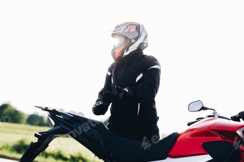 Preview: Woman preparing to drive a motorbike. Wearing gloves
