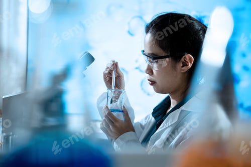 Preview: A woman in a lab coat is working with a beaker of liquid