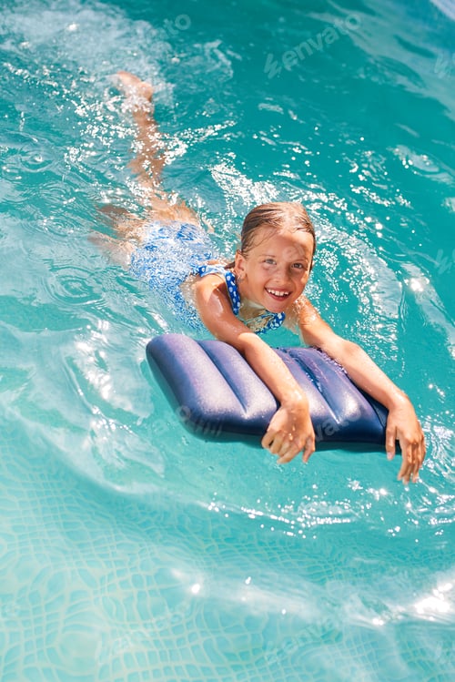 Preview: Happy little girl having fun in the swimming pool, dives and swim,