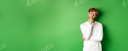 Preview: Thoughtful redhead man in glasses making choice, looking up and thinking, standing over green