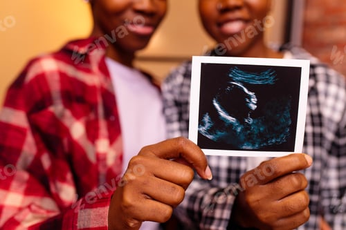 Preview: african american two happy future mothers sonogram image at home in evening