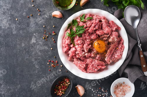 Preview: Raw minced meat. Ground meat beef, pork or lamb spices, herbs and eggs on white plate on black old c