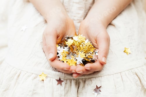 Preview: Close-up of gold and silver stars in children's hands. Party, new year celebration.