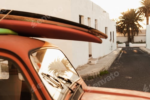 Preview: A stack of surfboards on a retro car roof with sun shining. Summer and surf background wallpaper.