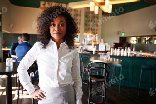 Preview: Female Manager Of Busy Cocktail Bar In Restaurant With Customers At Camera
