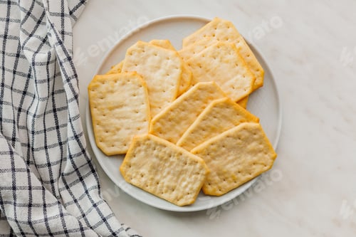 Preview: Golden Baked Crackers on plate on a White kitchen table. Top view.