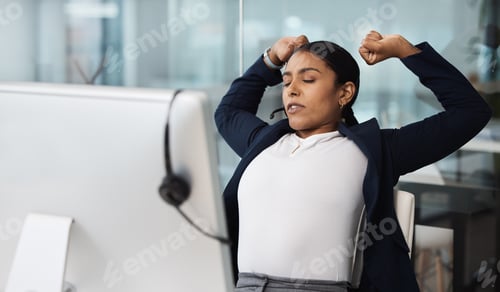 Preview: Shot of a young businesswoman stretching while working at her desk in a call centre