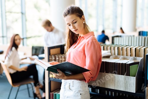 Preview: Beautiful woman reading a book in a library