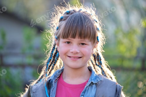Visualização: Retrato de uma jovem adolescente feliz e sorridente em roupas casuais com fitas azuis em longas tranças